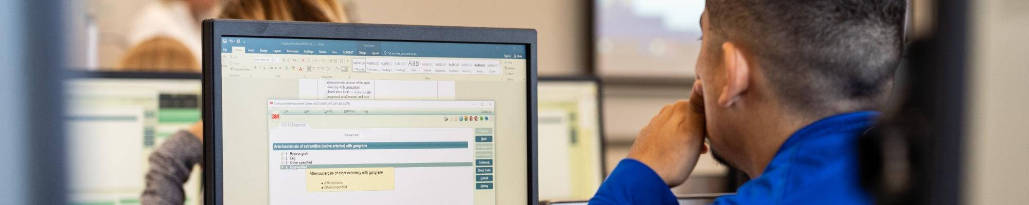 A Health Information Management Student looking at a computer screen